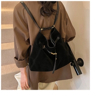 Detail of minimalist black suede tote bag showing dual shoulder straps and golden hardware