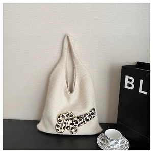 Detail of white knit tote bag featuring a Mama patch with leopard print and gold trim