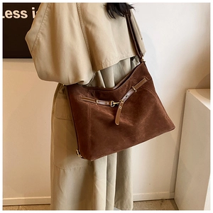 Detail of dark brown suede tote bag with leather strap and metal buckle closure