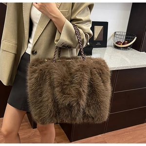 Detail einer großen braunen Kunstfell-Tasche mit geflochtenen Ledergriffen an einem Model