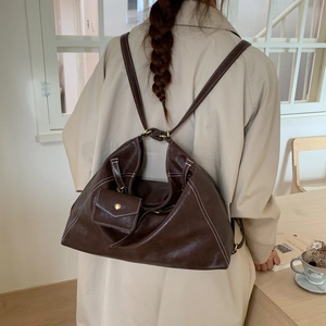 Détail arrière du sac à dos vintage en similicuir marron foncé avec surpiqûres blanches