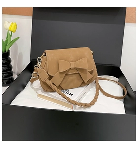 Detail view of khaki bow shoulder bag with woven handle in elegant gift box setup
