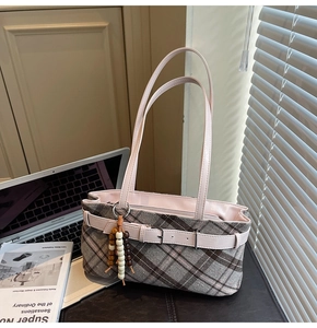 Detailed shot of checkered shoulder bag with pink leather strap and beaded charm