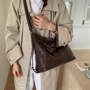 Détail du sac cabas marron vintage en cuir avec petite pochette sur un trench-coat chic