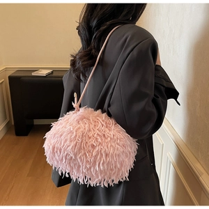Détail d'un sac à bandoulière en fausse fourrure rose sur une veste de costume noire