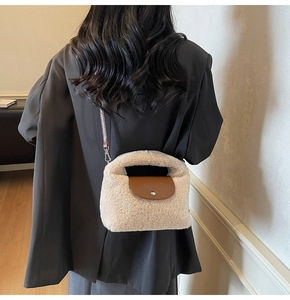 Détail du sac à main en peluche avec rabat en cuir marron sur un blazer noir