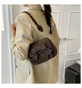 Detailed side view of brown suede crossbody bag with large bow and twisted rope strap