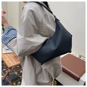 Sac croissant noir chic présenté dans un décor automnal chaleureux pour femmes