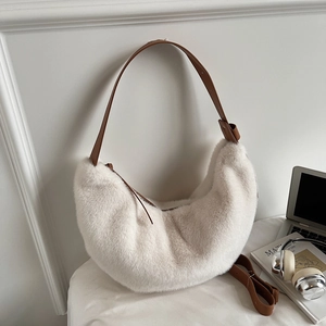 Close-up of white plush crescent bag with brown leather strap in a minimalist setting