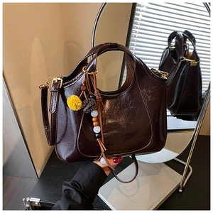Détail du sac cabas en cuir marron brillant avec pampille jaune et bouclerie dorée