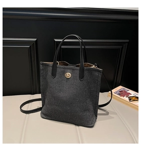 Detail of black denim bucket bag showing heavy texture fabric and gold twist lock