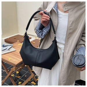 Détail d'un sac porté épaule croissant en cuir noir avec coutures verticales sur table