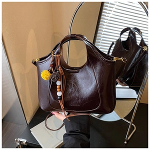Détail d'un sac hobo rétro en cuir brillant avec perles en bois et pompon