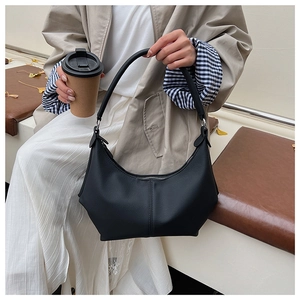 Gros plan d'un sac hobo noir porté par un mannequin dans une tenue urbaine élégante