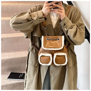 Detail of a brown leather backpack with white faux fur trim and metal chain accents
