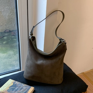Close-up of olive green matte suede hobo bag with vertical stitching and metal buckle