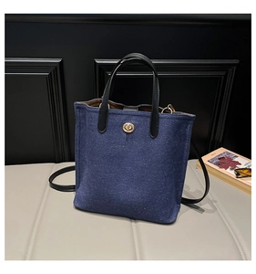 Detail of navy felt bucket bag with golden oval twist lock and black leather handle