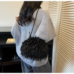 Détail d'un sac à bandoulière en fausse fourrure noire avec cordon et lanière en cuir