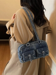 Retro blue denim shoulder bag with vintage wash finish and metal buckle pockets on casual model