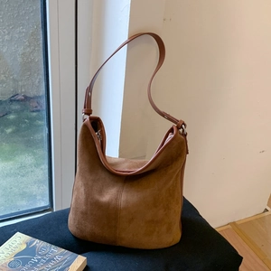 Close-up of brown suede shoulder bag showing vintage texture and decorative stitching detail