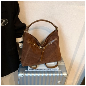 Detailed close-up of brown suede hobo bag with smooth leather straps and gold metal buckles