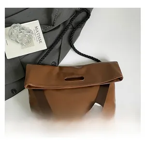 Detail view of brown leather tote bag featuring cutout handle and woven strap design