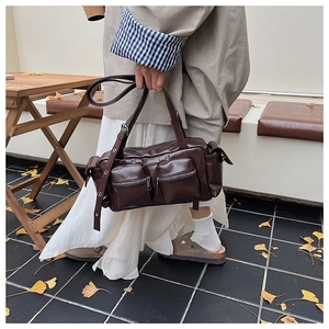 Detailed close-up of a vintage brown leather underarm bag with double front zip pockets