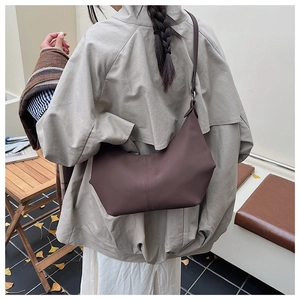 Vue détaillée du sac bandoulière en cuir marron porté en extérieur en automne