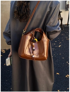Vue détaillée du sac porté épaule marron avec perles décoratives et pendentif en peluche