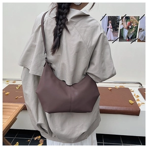 Sac demi-lune marron porté par un mannequin en trench-coat dans un décor extérieur