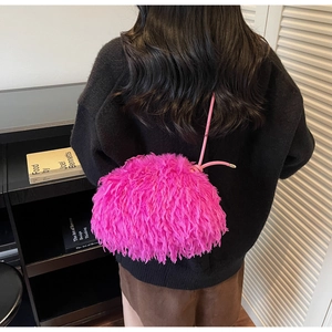 Gros plan d'un sac bandoulière en peluche magenta duveteux avec bandoulière en cuir