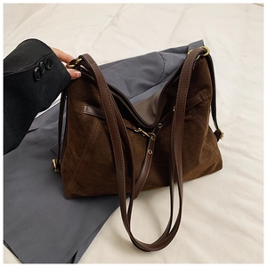 Macro shot of faux suede texture and bronze metal buckle on large brown tote bag