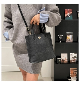 Close-up of retro grey denim tote bag featuring golden twist lock and leather shoulder strap