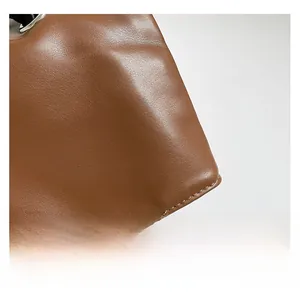 Close-up of brown leather texture and detailed stitching on a vintage tote bag