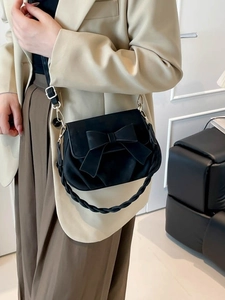 Chic black crossbody bag featuring a large bow accent and a woven top handle