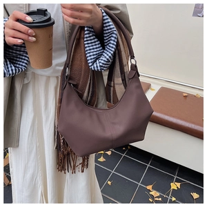 Détail d'un sac hobo marron mat tenu dans une scène de rue automnale très élégante