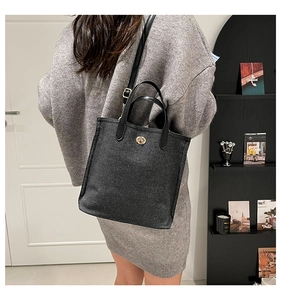 Macro detail of black canvas bucket bag with gold metal buckle and leather handle