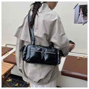 Side view of black faux leather shoulder bag with utility pockets worn by a model