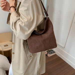 Brown frosted suede hobo bag on shoulder with adjustable leather strap detail