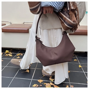 Vue détaillée du sac croissant marron foncé avec coutures dans un décor d'automne