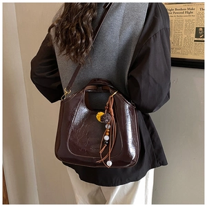 Détail du sac seau en similicuir marron foncé avec texture rétro huilée et pompon décoratif