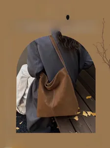 Winter fashion brown leather bucket bag shown on shoulder with minimalist seasonal styling