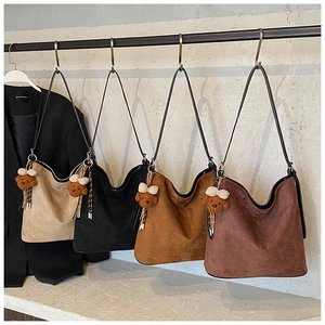 Detail of four retro suede tote bags in beige, black, and brown with cute bear charms