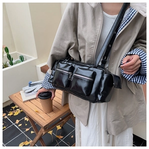 Detail shot of black shiny PU leather crossbody bag with dual functional zipper pockets