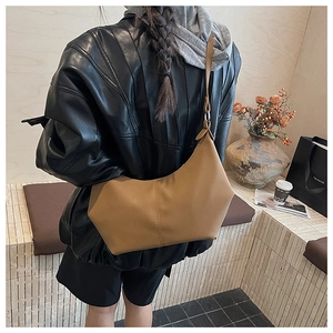 Détail du sac demi-lune en similicuir caramel avec couture verticale centrale élégante