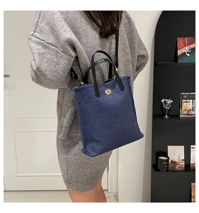 Close-up of blue denim mini tote bag featuring black leather handles and gold twist lock
