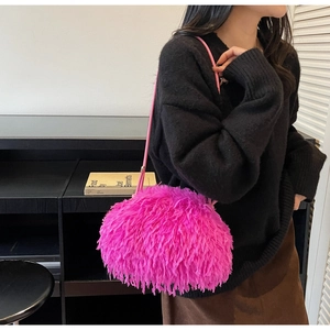 Vue détaillée d'un sac à bandoulière en fausse fourrure rose vif sur un pull noir