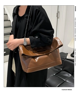 Detail of brown leather tote bag featuring a decorative black and white woven strap