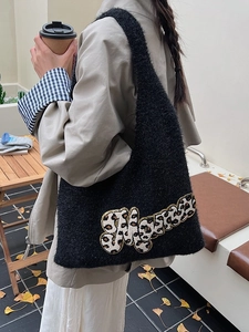 Large black plush knit tote bag with leopard print letter design in an outdoor setting