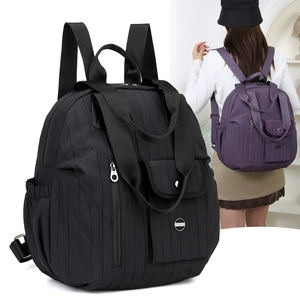 Detail view of black quilted nylon travel backpack and purple variant worn by a model